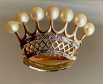 BROCHE EM FORMA DE COROA EM OURO 18K COM PÉROLAS E DIAMANTES. Broche em ouro amarelo 18k, representando coroa estilizada, com estrutura vazada e decoração superior em hastes arqueadas, cada uma encimada por pérolas esféricas de tonalidade creme. A base apresenta ornamentos em relevo com aplicação de faixa em metal branco (platina ou ouro branco), cravejada com pequenos diamantes em lapidação antiga, formando frisos decorativos de inspiração geométrica. Composição típica do período anos 1920/30, combinando leveza estrutural e contraste entre ouro amarelo e topo branco, característico da joalheria de transição Belle Époque / Art Déco. Medidas: 4,0 x 3,0 cm.Peso: 6,22 g. Material: ouro 18k. Pedras: pérolas naturais/cultivadas e diamantes Fecho tipo alfinete com trava.