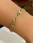PULSEIRA EM OURO AMARELO 14K COM ÁGUAS-MARINHAS. Pulseira em ouro amarelo 14k, composta por elos articulados em desenho vazado, intercalados por seis gemas ovais de água-marinha, lapidação mista (facetas superiores com fundo levemente abaulado), cravadas em chatões ovais. As pedras apresentam coloração azul-clara característica, com boa transparência e brilho vítreo suave, compondo conjunto elegante de leitura leve e contínua no pulso. Modelo de estética clássica, com provável produção da segunda metade do século XX, possivelmente de origem brasileira tipologia recorrente em joalheria nacional do período. Comprimento: 19 cm. Peso: 12,70 g. Material: ouro 14k. Pedras: 06 águas-marinhas naturais (lapidação oval). Fecho tipo lingueta com trava de segurança. Observação técnica: As gemas apresentam pequenas inclusões naturais e leve variação de tonalidade compatíveis com águas-marinhas naturais, sem prejuízo ao conjunto estético.