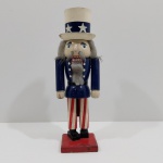 Boneco Quebra Nozes de Madeira, Com Detalhes na Pintura e um Quebrado no Chapéu (Necessita Restauro). Medidas: Altura: 35 cm, Largura: 8 cm, Comprimento: 11 cm, Peso: 670 g.