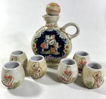 GARRAFA E SEIS COPINHOS EM CERÂMICA CERAMARTE, DECORAÇÃO EM ALTO RELEVO FIGURAS GERMÂNICAS. MEDIDAS: GARRAFA 17 X 12 CM / COPINHOS 5,5 CM DE ALTURA.