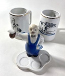 TRÊS PEÇAS EM CERÂMICA SENDO DUAS CANECAS DE CHOPP E UM SUPORTE PARA COPINHOS COM FIGURA MASCULINA. MEDIDAS: