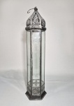 Grande lanterna marroquina para uma vela, metal cinzelado e fenestrado. Laterais com placas de vidro. Porta frontal. Gancho de suspensão. Med. 60 cm com o gancho.