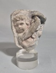 Antigo fragmento de relevo com figura de Putti e instrumento musical no estilo clássico greco romano. Base em acrílico. Med. 14.5 cm