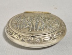 Antiga caixa oval porta-comprimidos em metal branco, decorada com relevos e figuras. Med. 7 x 5 cm