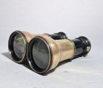 EUROPA, SÉC.XIX/XX - Antigo binóculo em latão com 3 configurações de lentes: Theater, Landscape e Marine (Marítimo). Final do período vitoriano/Eduardiano, entre 1880 e 1910. Medidas aberto: 14 x12 cm. INFORMAÇÕES SOBRE:  As Três Configurações ("Tri-Lens" ou "Three-Power"): Na virada do século XIX para o século XX, tornou-se muito popular o mecanismo de "óptica tripla". Ao girar uma pequena roleta (geralmente perto das oculares), o usuário mudava internamente o jogo de lentes para se ajustar ao ambiente:Theater (Teatro): Menor ampliação, mas campo de visão mais amplo e luminoso para ambientes fechados.Landscape (Paisagem): Ampliação média para uso geral ao ar livre.Marine (Marítimo): Maior ampliação e foco para longas distâncias no mar ou campos abertos.Materiais de Fabricação: O corpo estrutural feito em latão (que ganhou essa pátina escura com o tempo) e o revestimento dos tubos em couro legítimo (que apresenta o desgaste natural dos anos na imagem 26161511.jpg) são a assinatura clássica dos instrumentos ópticos dessa era.Design Galileano: Eles utilizam o sistema de lentes de Galileu (tubos retos, sem os "ombros" ou curvas que os binóculos modernos com prismas de Porro possuem).