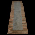 Passadeira tibetana  com borda listrada e centro liso, medindo 404 x 106 cm.