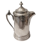 MF.D & PLATED BY READ & BARTON - Grande tankard em metal inglês. Espessurado a prata. Apresenta bojo lavrado com brasão e iniciais, não identificadas. No fundo marcado: MFD & Plated By Read & Barton - Patented, 1868. 36 x 27 x 19 cm.