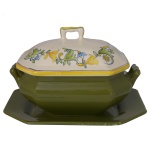Terrina com seu presentoir em cerâmica brilhante, da manufatura nacional Luiz Salvador, Itaipava. Terrina de formato retangular, sendo o bojo na cor verde musgo e a tampa  de fundo bege com decoração floral amarela com azul. Presentoir também retangular na cor verde. 20 cm (MT). 18 x 27 x 17 cm (terrina). 30 x 24 cm (presentoir).