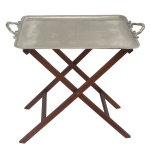 Mesa de apoio estilo butler table. Bandeja duperior feita de metal prateado Ercuis com acabamento liso e bordas elevadas. Possui duas alças ornamentadas nas laterais para facilitar o transporte. Base de Apoio com estrutura em formato de "X" confeccionada em madeira escura. Ela é articulada e pode ser dobrada completamente para economizar espaço quando não estiver em uso.