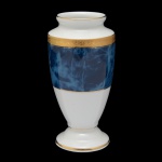 NORITAKE - Vaso em porcelana de formato balaústre, ornamentado à meia altura por larga faixa em tons mesclados azuis e realçado por filetes a ouro. Bojo abaulado com gargalo em corneta e base circular cônica. Sob a base, marca da manufatura no Sri Lanka. 17 cm.