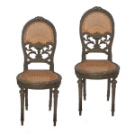 Brasil. Séc. XIX - Par de cadeiras em madeira nobre, estilo neorrococó. Encostos ovalados com tabelas ornamentadas por vasos com palhinha da Índia, apoiados em adornos florais vazados. Assentos arqueados sobre largas molduras, sustentados por pernas retas e torneadas com anelados. 95 x 41 x 35 cm.