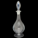 Decanter em cristal translucido. com detalhes gravados com motivos botânicos como folhas de parreira e uvas. Corpo bojudo, gargalo estreito. Tampa na forma de pinha facetada. 32 x 11 cm.