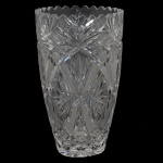 Vaso floreiro em cristal tcheco, lapidado e translúcido. Apresenta cortes geométricos como padrões de estrelas e sulcos, comuns em peças tchecas. 31 x 18 cm.