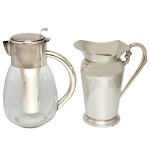 Conjunto de duas peças, sendo: A) jarra Refresqueira feita de vidro lapidado com estrelas, apresentando alça, bocal, tampa e um recipiente interno para gelo em metal prateado. (28 x 20 cm). B) Jarra para água em metal Eberle (12 x 20 cm) e jarra para suco