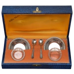 Conjunto composto por saleiro e mostardeira com seus presentoirs. Recipientes em cristal (2 x 4 cm), presentoir e colheres em metal prateado nacional da manufatura Aurea Prata 90. Acondicionados em estojo original (6 x 20 x 10 cm).