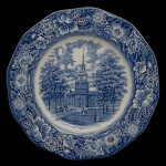 STAFFORDSHIRE LIBERTY BLUE. Enoch Wedgwood & Co. Inglaterra - Prato raso em porcelana inglesa com o tema Independence Hall. Feito em comemoração ao bicentenário americano para o Benjamin Franklin Federal Savings and Loan Bank em meados da década de 1970. Apresenta fio de cabelo. 26 cm.