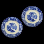 W. H. GRINDLEY. Padrão Shanghai. Inglaterra - Par de pratos em louça inglesa padrão "Shanghai", conhecido como "flow blue" ou azul borrão. Apresenta paisagens orientais com castelos e pagodes. 18 cm.