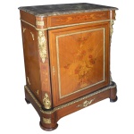 Séc. XIX - Rica cômoda Dunquerque estilo Império, com belas proporções, em madeira nobre. Apresenta fina ornamentação em marqueterie, realçada por profusos adornos em bronze ormolu. Tampo retangular em mármore cinza rajado, com quinas recortadas. Caixa reta, com segmento superior ornado por ramos com folhagens e friso em godrões. Centro apresentando porta acompanhando o estilo, exibindo exuberante cesta florida, emoldurada por filetes. Colunatas laterais ornamentadas por bustos de cariátides, rematadas por composições estilizadas. Base saliente e retilínea, com pés recortados em arcos sobre sapatas. 100 x 75 x 45 cm.