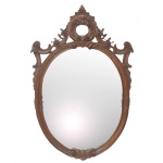 Espelho de parede de formato oval, com moldura em madeira lustrada, lavrada e ornada por frisos canelados, folhagens e volutas. Frontão ornamentado por vazados com arabescos, ramalhetes e lóbulos drapeados. 113 x 74 cm (MT)..