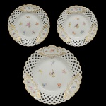 MEISSEN  Belíssimo conjunto para sobremesa em porcelana alemã da manufatura Meissen. Acabamento ornamental de borda rendada vazada e detalhes florais ao centro. Formato redondo clássico com aba inteiramente vazada em padrão de treliça geométrica imitando renda.  21 cm (menor). 28 cm (maior).