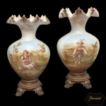 BACCARAT, France - Raro e belo par de vasos franceses em opalina leitosa, de formato piriforme, ornados por largas bordas reviradas e onduladas. Bojos abaulados, ornamentados por delicadas cenas campestres realçadas por casal de crianças. Bases em bronze lavrado, adornadas por frisos de godrões, sustentadas por pés em volutas rematados por folhagens. 40 x 22 cm.