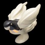 GOEBEL, W. Gerrmany  Escultura em porcelana alemã, representando pássaro com as asa abertas. Sob a base marcas da manufatura. Design moderno em branco e preto e detalhes dourados. A marca é conhecida por sua porcelana de alta qualidade e detalhes artísticos. 18 x 25 x 16 cm.