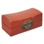 Caixa chinesa com tampo no formato de travesseiro retangular revestida em laca rouge de fer, ornamentada em policromia por ramos floridos. Apresenta frente com fecho circular em metal. Parte interna forrada com papel impresso. 7 x 17 x 7 cm. Pequenos defeitos na pintura, e marcas de uso na laca.