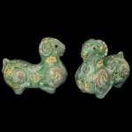 Par de caixas chinesas no formato de carneiros em porcelana policromada, amarelo sobre fundos verdes. Apresentam decoração com adornos geométricos e estilizados em amarelo, aubergine e azul claro. Interiores em azul celeste. 15 x 20 x 10 cm.