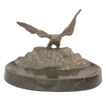 Porta-cartão ou escultura em bronze representando uma águia com asas abertas sobre uma rocha. A base mármore belga. Assinada. 14 x 20 x 14 cm.
