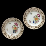 MEISSEN. Alemanha -  Par de pratos circulares em porcelana alemã. Apresentam bordas vazadas (técnica conhecida como openwork) e central com a clássica decoração com buquê de flores em policromia. 23 cm.