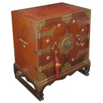 Armário baixo de estilo oriental em madeira vermelha com ferragens de latão. Apresenta características de mobiliário chinês, confeccionado com 2 portas frontais e uma madeira com veios marcantes e vários apliques metálicos funcionais e decorativos. 50 x 54 x 30 cm.