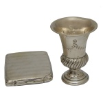 Lote constando de 2 peças, sendo: A) cigarreira em prata de lei com contraste de teor 800 mls. (9 x 8 cm / 80 gramas) e 1 porta cigarros de metal na forma de taça. (9 x 7 cm).