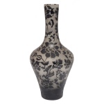 Belíssimo vaso de formato balaústre decorativo contemporâneo feito de vidro jateado apresentando uma sofisticada ornamentação de estilizações de flores, volutas e folhagens barrocas que cobrem todo o bojo e o longo gargalo. na cor preta contra um fundo translúcido. 42 x 20 cm.