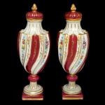 LIMOGES  Par de potiches em porcelana francesa policromada e dourada, de formato alongado, moldados com gomos torcidos. Bojos abaulados, ornamentados por faixas alternadas com flores, estilizações e folhagens. Gargalos retraídos em corneta, encimados por tampas semiesféricas com pegas em ponteiras. Bases com anelados, apoiadas em pés cônicos sobre peanhas quadrangulares. Marca da manufatura no verso. Uma das peças com restauro e trincados, necessitando de novos restauro (no estado) 32 x 11 cm.