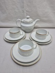 Lote de bule com 3 trios de chá com bolo em porcelana. Medindo o bule 15,5cm de altura com tampa, fio de cabelo na alça. Com desgaste no friso.