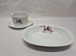 Travessa e molheira em porcelana Renner Medaillon com flor roxa e friso ouro. Medindo a travessa 23,5cm x 15,5cm x 4cm de altura, molheira 10,5cm x 8cm de altura.