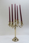 Elegante candelabro para cinco velas, base redonda, haste facetada e quatro braços curvos em metal dourado. Md. 40 x 32 cm.