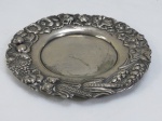 METAL PRATEADO, uma (1) salva com borda decorada em relevo com frutas, flores e trigais. Med. 15 cm diâmetro.