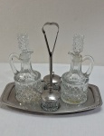 Galheteiro com 2 galhetas para azeite e vinagre de vidro moldado, encimado por bandeja com alça retrátil e dois potes com tampa para sal e pimenta. Med. 23 x 27 cm x 17 cm.