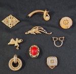 Lote com nove (09) peças, composto por três prendedores para pontas de lenço/echarpe  e cinco broches em metal dourado.