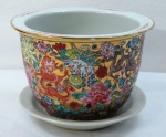 Cachepot com prato em porcelana oriental, esmaltado em farta policromia com decoração floral e dragões, sobre fundo dourado. Medindo: 15 x 20 cm.