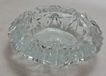 Elegante cinzeiro em cristal europeu, translúcido, borda recortada e movimentada, lapidado com navetes em faixas intercaladas por dupla canelura, fundo estrelado. Med.: 5 x 16 cm.(apresenta ínfimos bicados).