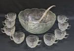 Poncheira em grosso vidro prensado decorado em relevo com florões e folhagens. Acompanha nove canecas com alça no mesmo padrão e uma concha em acrílico translúcido. Med. 15 x 32 cm.