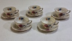 KOENIGSZELT (1945 - 1957, Polônia), Cinco (05_) xícaras para café com pires confeccionados em porcelana polonesa esmaltada na tonalidade marfim, ricamente decorado com florais  e guirlandas e frisos  a ouro. Marcados no verso Koenigszelt Made in Poland.