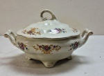 KOENIGSZELT (1945 - 1957, Polônia), Grande terrina, base com quatro pés, alças laterais e tampa com pega vazada confeccionados em porcelana polonesa esmaltada na tonalidade marfim, borda moldada, ricamente decorado com florais  e guirlandas e frisos  a ouro. Marcados no verso Koenigszelt Made in Poland. Med. 19 x 29 cm diâmetro entre alças.