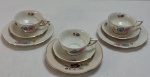 KOENIGSZELT (1945 - 1957, Polônia), Três ternos com três xícaras para chá, três  pires e três pratos para bolo ( um adaptado com mínima diferença no floral), confeccionados em porcelana polonesa esmaltada na tonalidade marfim, ricamente decorado com florais  e guirlandas e frisos  a ouro. Marcados no verso Koenigszelt Made in Poland. Med. 20 cm diâmetro.