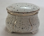 MADE IN ITALY- Caixas porta-joias em porcelana no formato "cômoda bombê" no tom branco salpicado em preto com dourados. Tampa articulada. Assinatura do designer na tampa, marcado na base. Med. 14 x 18 x 13 cm.