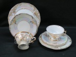 MAUÁ-   Dois (02) ternos em porcelana iridescente, moldada na pasta, guirlandas em relevo em farta douração. Med. prato para bolo 18,5 cm.