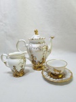 Jogo de bule, leiteira e xícara de café em porcelana Schmidt pintada à mão com ouro. Medindo o bule 17,5cm de altura.