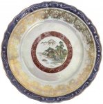 Prato decorativo em porcelana brasileira Porcelana Mauá, com cena oriental ao centro, borda ricamente ornamentada em douração, faixa iridescente e relevo em azul. Peça de apelo decorativo, apresentando sinais de uso e desgaste do tempo. Mede 23cm.